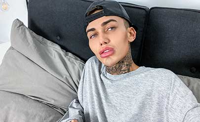 Tattooed Logan runs his hands over his slim torso, pushing up his grey sweatshirt to show his abs and chest, and slipping his other hand down the front of his black trousers.
