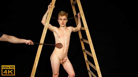 Sexy Jan Blatnik is naked and gagged and shackled to a step-ladder as his rock hard cock pokes out in front of him. His balls are tied too.